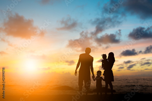 Silhouette family mother, father and young son holding hands, ta