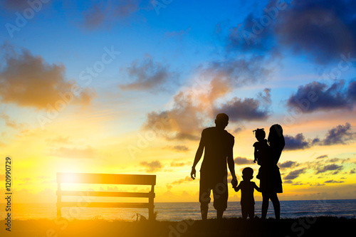 Silhouette family mother, father and young son holding hands, ta