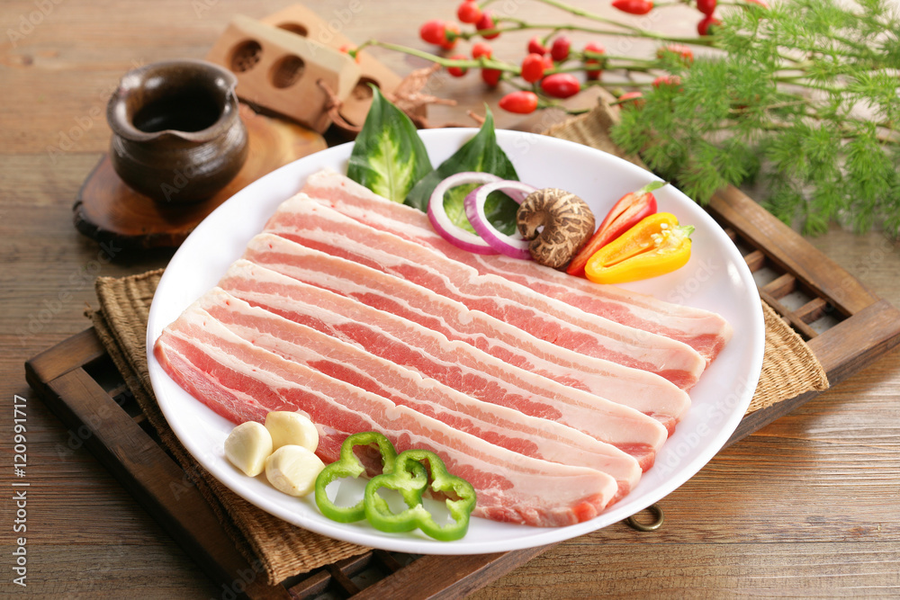 Sliced fresh Pork meat on white plate with herbs and chili Sliced fresh Pork meat on white plate with herbs and chili