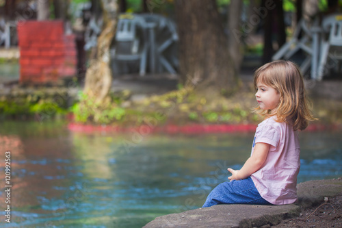 Fototapeta Naklejka Na Ścianę i Meble -  Kind sitzt alleine an einem See