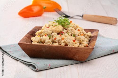 Tofu stir soboro on wooden bowl with tomato and onion on tablecl photo