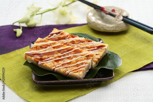 Real firmer okonomiyaki on green leaf and black plate in Japanes