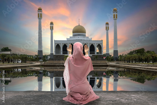 Concept of religion Islam. woman praying on the background of a mosque at sunset