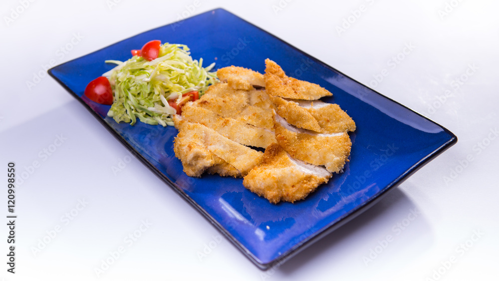 Fried breaded chicken with salad on blue chinese plate on white Fried breaded chicken with salad on blue chinese plate on white