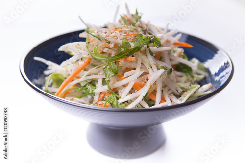 Daikon salad on blue chinese plate on white background