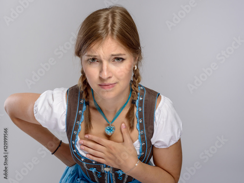 Junges Mädchen im Dirndl hält ihren Ausschnitt zu vor unsittlichen blicken photo