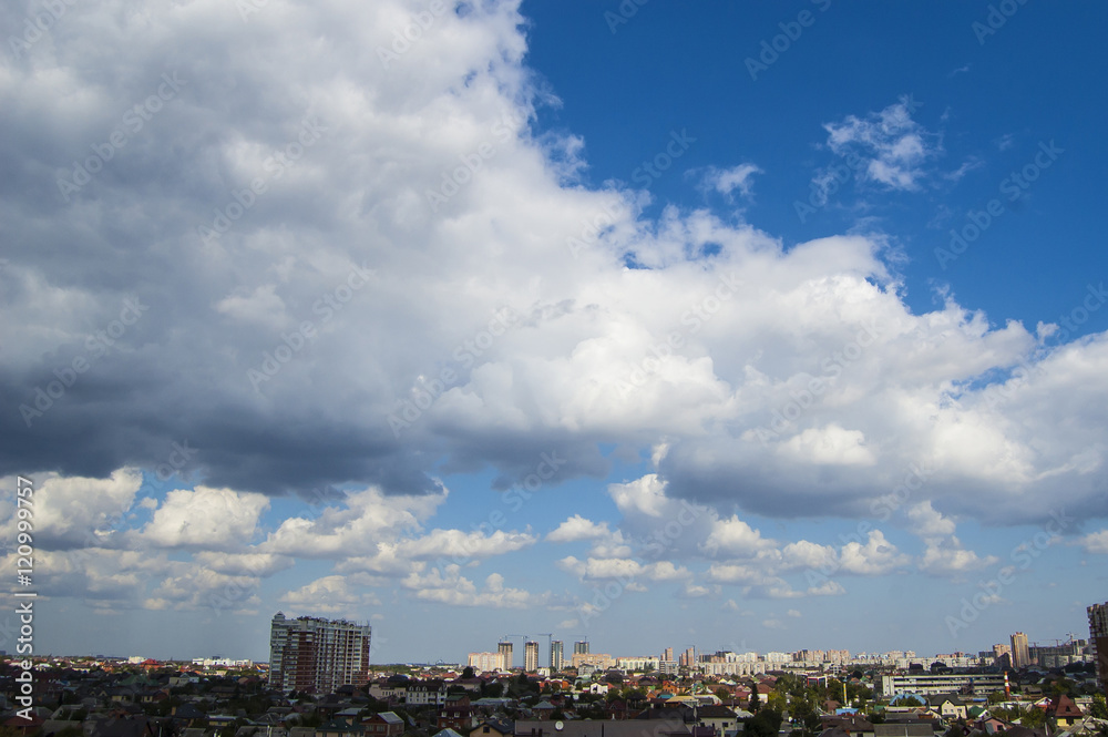 Blue sky with white cumulus clouds above the city