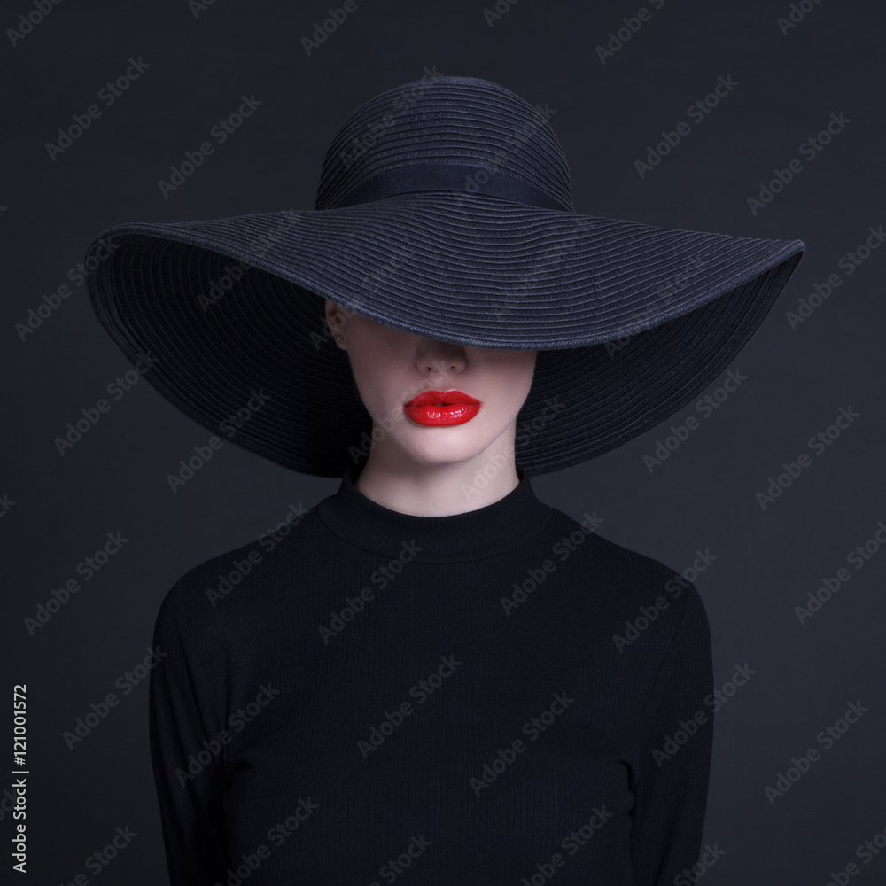 Luxury woman in a large black hat and bright lips on black background Luxury woman in a large black hat and bright lips on black background