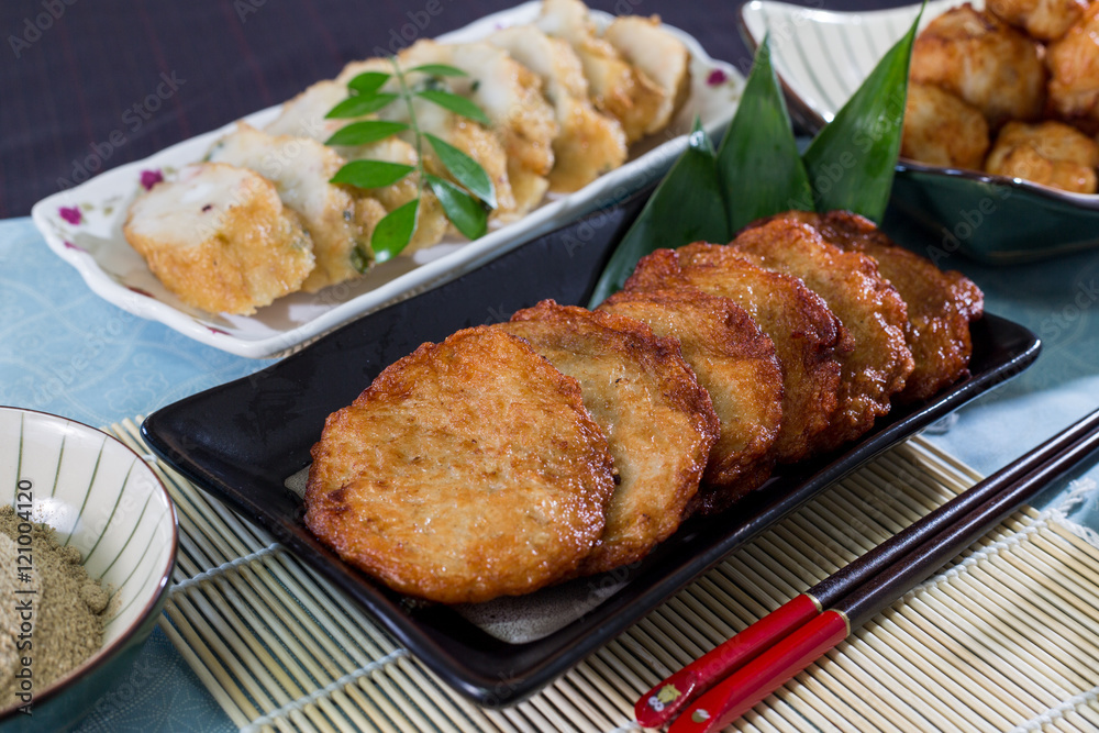 Fried fish cake on black plate on bamboo tray in restaurant