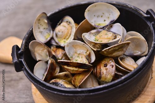 Garlic white wine clam in black pot on wooden tray in asian rest