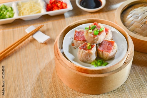 Dishes of ham dumplings on bamboo tray in asian restaurant