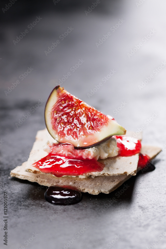 Appetizer canape with fig, jam and cheese on a small loaf of bread, closeup, selective focus Appetizer canape with fig, jam and cheese on a small loaf of bread, closeup, selective focus