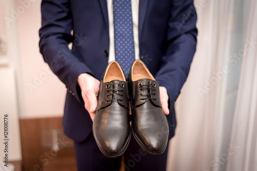 Businessman hold classical black shoes to cloth up
