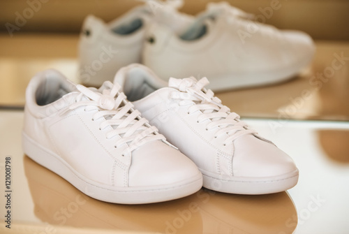 Youth white sneakers with white untied the laces on wooden background