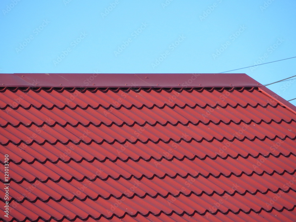 Red modern roof covered with tile effect PVC coated metal roof sheets against a blue sky Red modern roof covered with tile effect PVC coated metal roof sheets against a blue sky