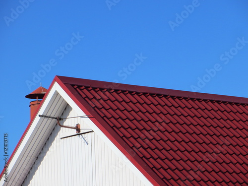 Red modern roof covered with tile effect PVC coated metal roof sheets against a blue sky