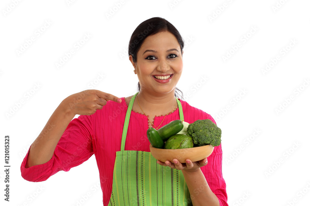Smiling female chef holding bowl full of vegetables and fruits Smiling female chef holding bowl full of vegetables and fruits