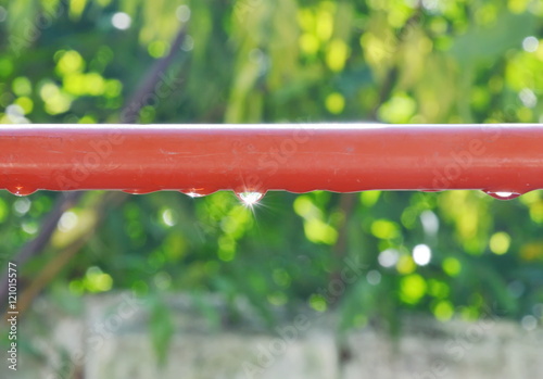 drop of water on red aluminum clothes line reflection sunlight