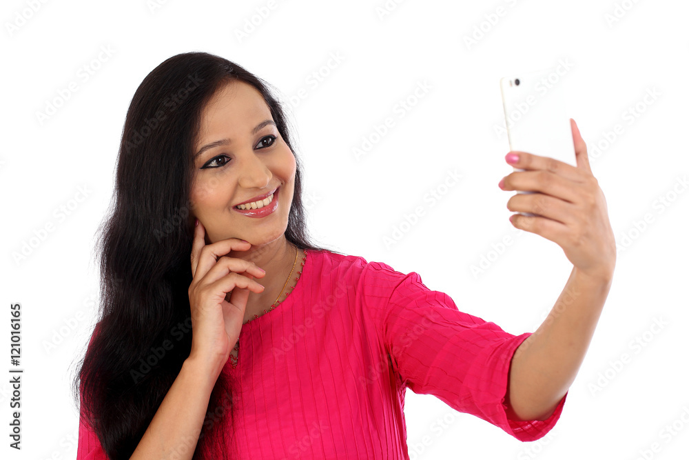 Happy young woman taking a selfie against white background Happy young woman taking a selfie against white background