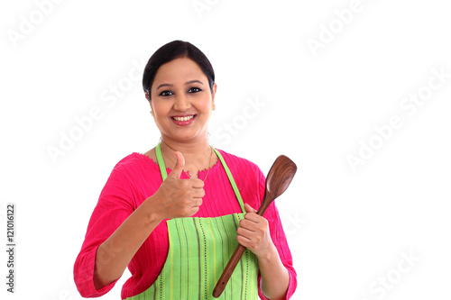 Happy young woman holding kitchen utensil against white backgrou