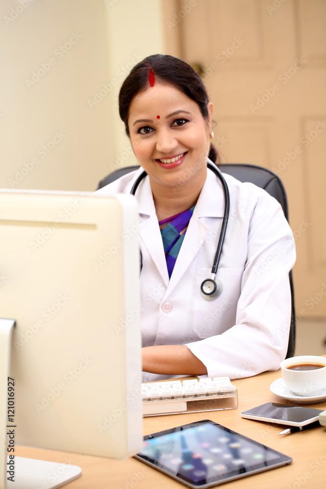 Traditional female doctor holding tablet computer at clinic desk Traditional female doctor holding tablet computer at clinic desk
