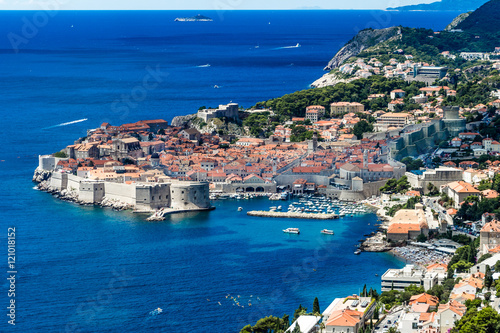 Fortified Dubrovnik Old Town surrounded by a blue Adriatic Sea under a sunny and hot summer day. This Croatian Mediterranean city is famous for its beaches and touristic boat trips from its harbour.