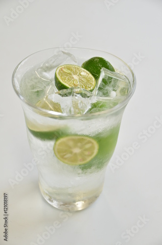 Glass of green kumquat juice with cold ice on white background