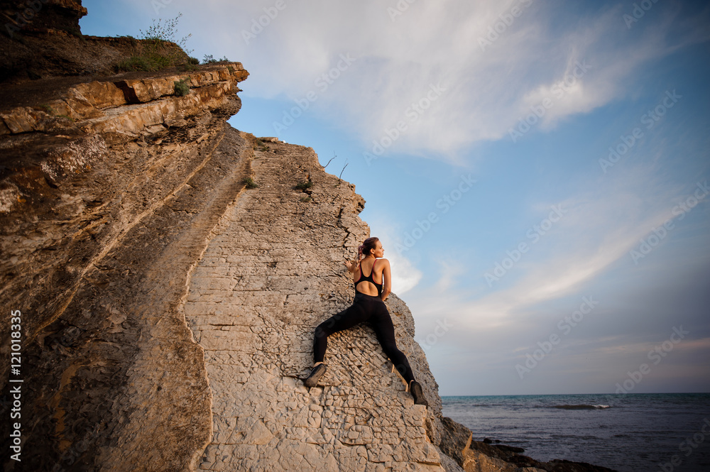 female rock climber climbs on rocky wall