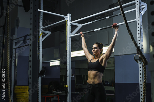 Concept: power, strength, healthy lifestyle, sport. Powerful attractive muscular woman CrossFit trainer do pull ups during workout at the gym