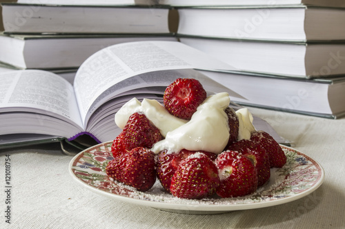 deser z świeżych polskich truskawek z bitą śmietaną na tle książek