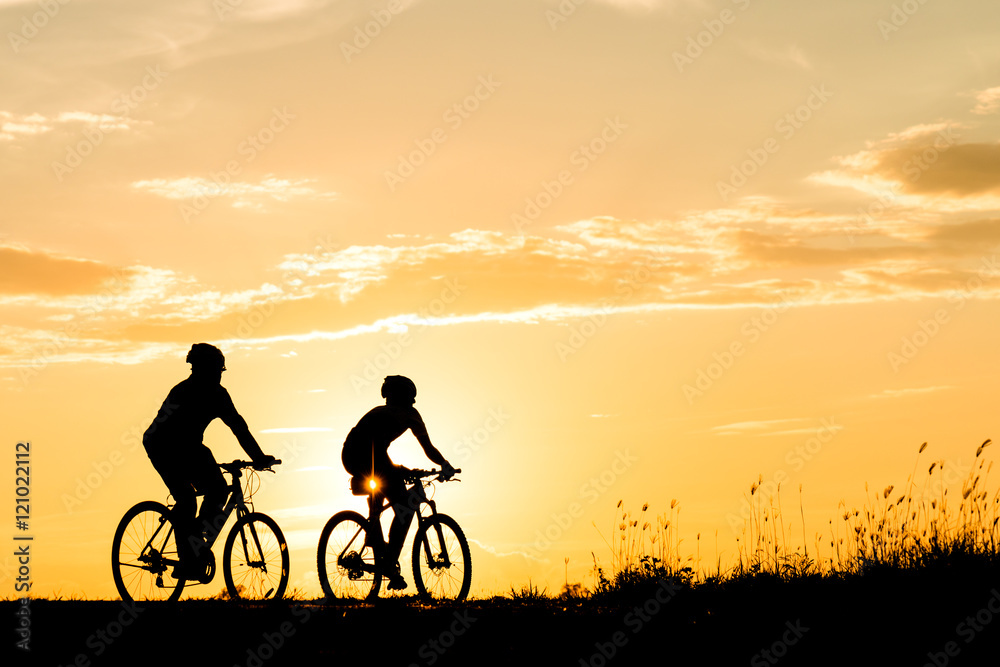 Silhouette of cyclist with friend motion on sunset background