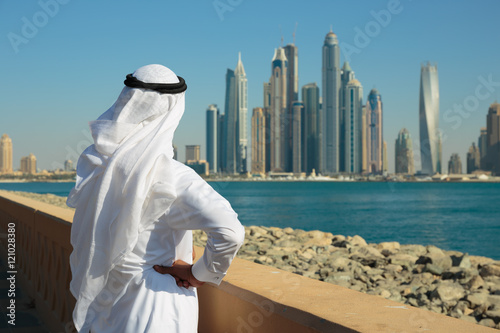 Photography Modern buildings in Dubai Marina,, UAE. Man in Arab dress looks