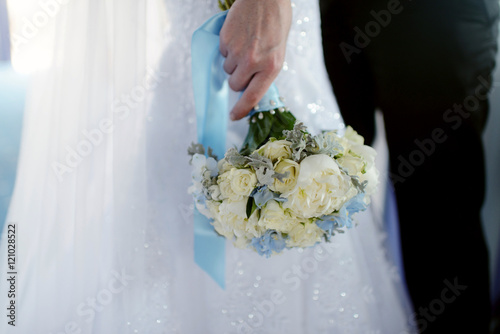 Wedding couple with bouquet. Female and male portrait. Beautiful model girl in white dress. Man in suit. Beauty bride with groom. Woman in bridal gown. Cute lady and guy indoors