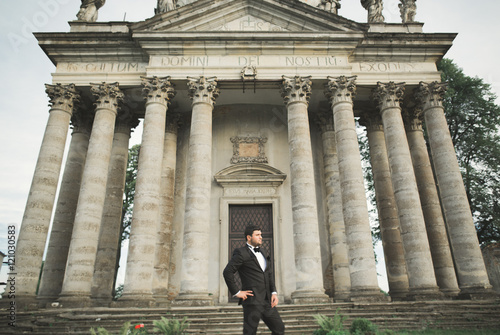 Stylish groom posing on background old castle