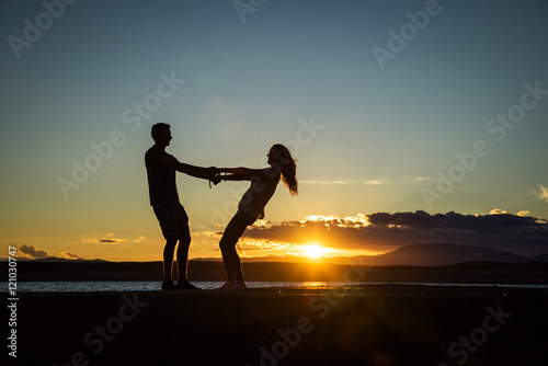 Couple playing  enjoying each other on the beach with a beautiful sunset in background