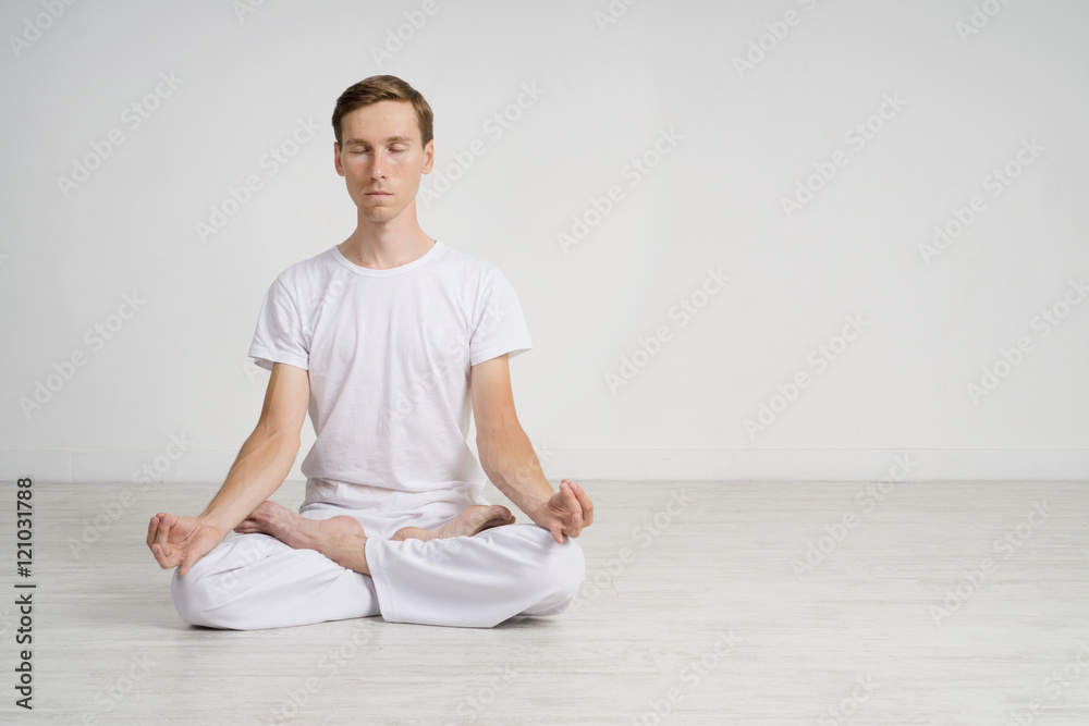 Young man meditating in Lotus position on the floor Young man meditating in Lotus position on the floor