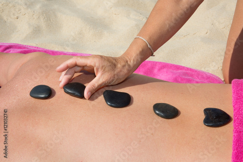 Man relaxing with hot stones on back before massage, beach