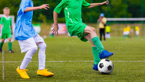 Fototapeta Naklejka Na Ścianę i Meble -  Football soccer game of youth teams. Running young players kicking soccer ball on sports field