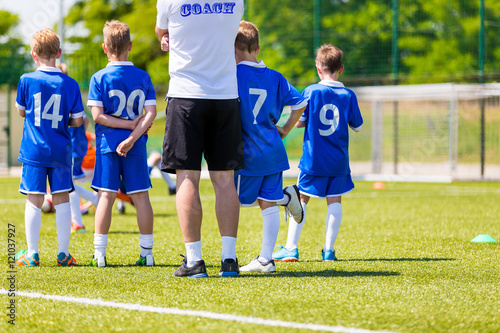 Young Boys In Soccer Football Team With Coach. Reserve Players on a Team Bench. Motivation Talk Before Soccer Match. Little League Soccer Boys Team.