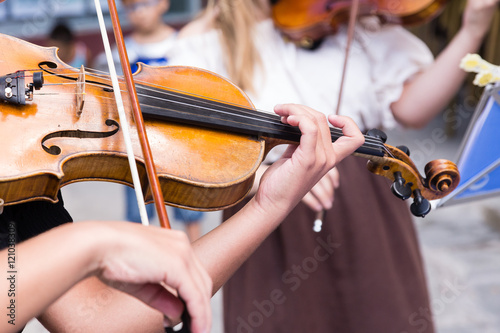 young musician playing the violin on the streets of a city
