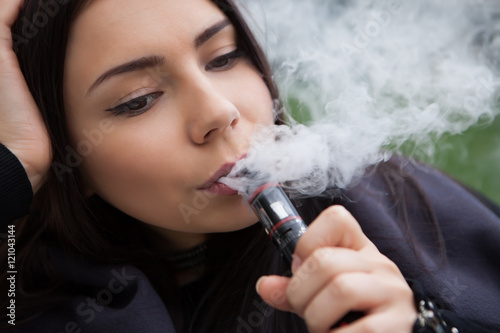 Pretty young girl smoking electronic cigarette  photo