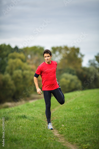 Young man stretching his legs before his daily run 