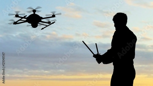 Man operating a drone at sunset using a controller