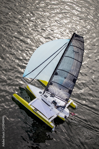 Luftaufnahme: Trimaran auf spiegelndem Wasser, Gegenlicht