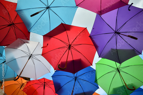 Colorful umbrellas of different bright colors with parts of cloudy sky