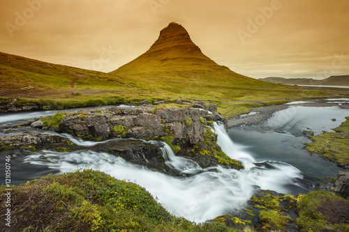 orange sunset with rock and waterfall in Iceland