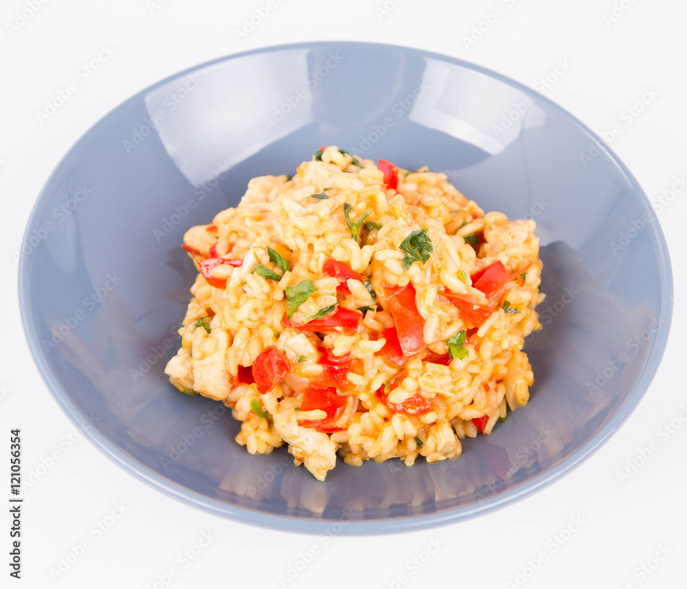 Risotto with chicken, tomatoes, bell pepper, onion, parsley and garlic on a blue plate on a wooden background Risotto with chicken, tomatoes, bell pepper, onion, parsley and garlic on a blue plate on a wooden background