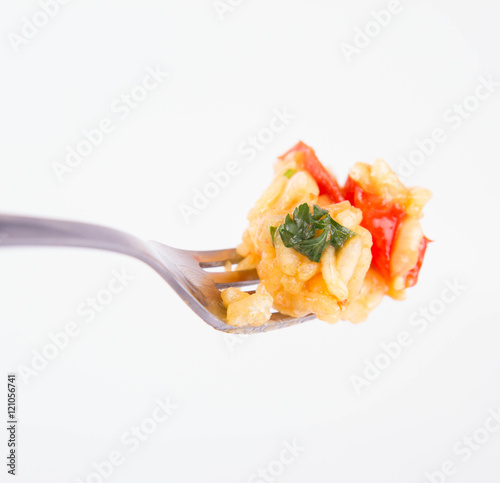 Risotto with chicken, tomatoes, bell pepper, onion, garlic and parsley on a fork on a white background 