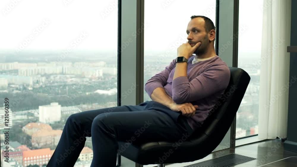 Pensive man sitting on chair and admire view from window at home
