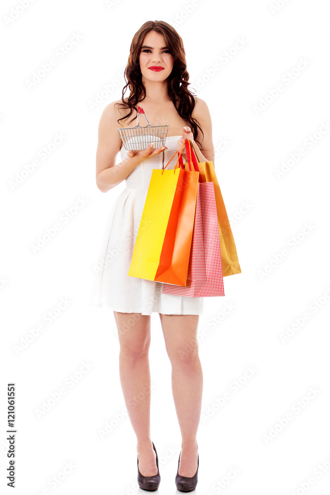 Young woman holding small empty shopping basket and shopping bags